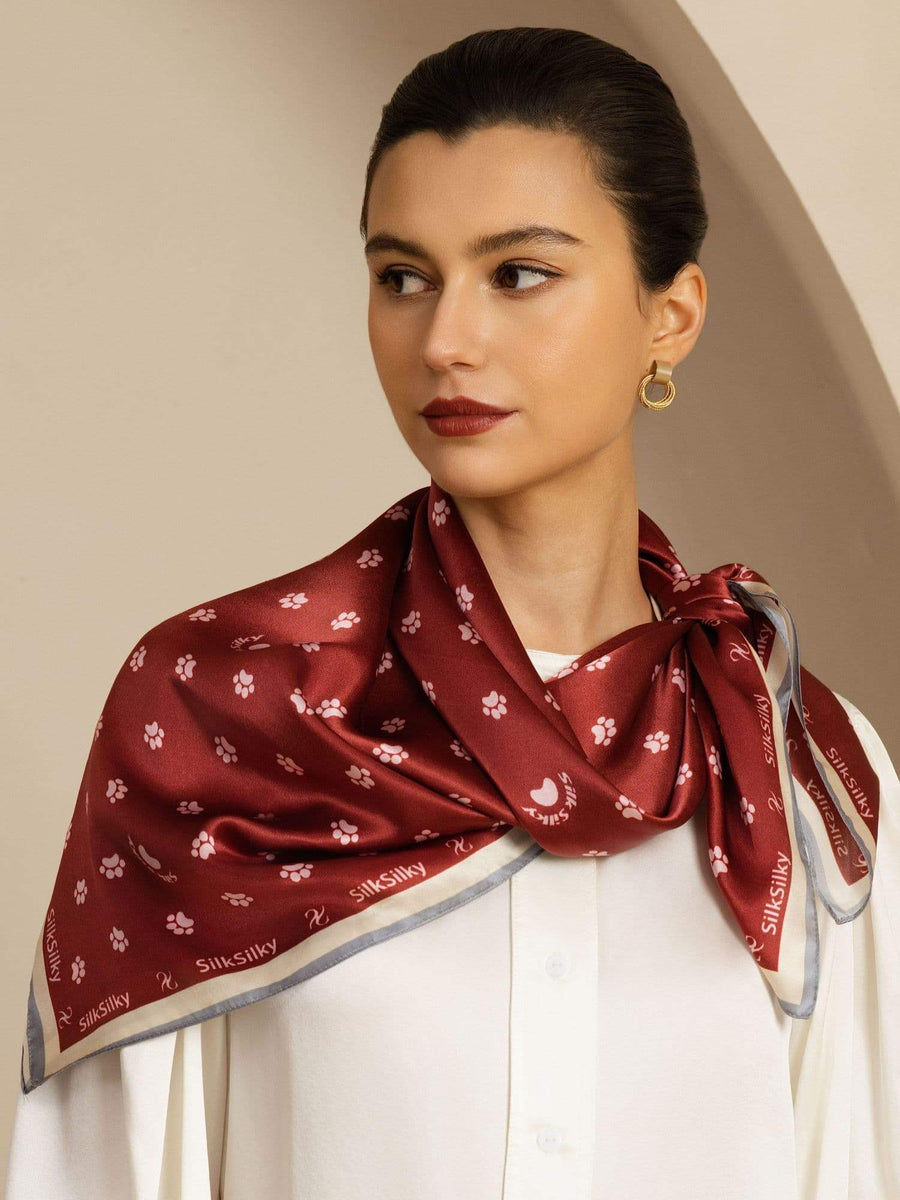 Mulberry silk scarf, red with white paw print and floral pattern, tied around a woman's neck.