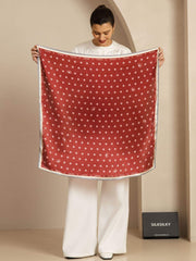 Red mulberry silk square scarf with white paw print pattern and blue border, held by a woman.