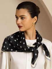 Black mulberry silk scarf with white paw print pattern, tied on a woman.
