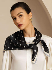 Black 100% Mulberry silk square scarf with white paw print pattern, tied around a woman's neck.