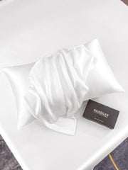 White mulberry silk pillowcase with envelope closure and a black gift box on a white bed.