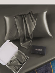 Dark gray mulberry silk pillowcase with envelope closure, folded in a box, and a black gift box.