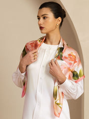 Woman wearing a pink floral print mulberry silk scarf over a white shirt.