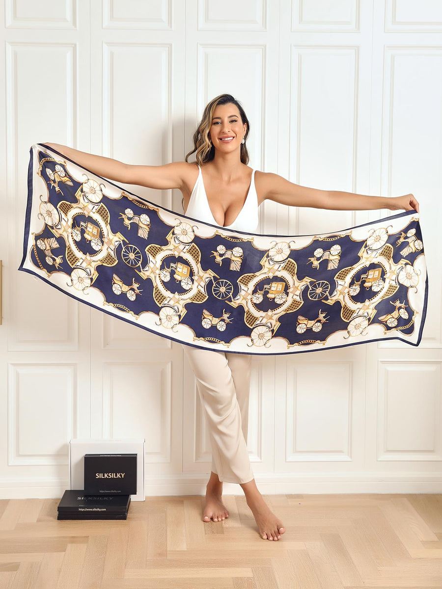 Woman holding a long mulberry silk scarf with a navy blue and gold carriage print.