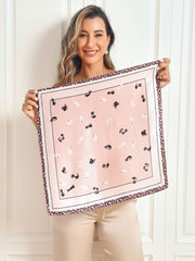 Woman holding a pink mulberry silk square scarf with black cat print and leopard border.