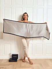 Woman holding a long mulberry silk printed shawl scarf with a geometric pattern and dark border.