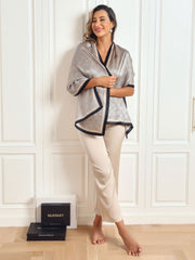 Woman wearing a mulberry silk printed long rectangle shawl scarf with black trim, paired with beige pants.