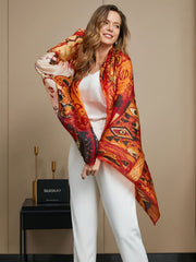 Woman wearing a vibrant orange and red mulberry silk printed rectangle scarf, 175x105cm, over white attire.
