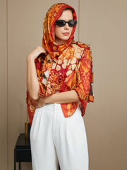 Women's mulberry silk printed rectangle scarf in vibrant orange and red, styled as a head covering.