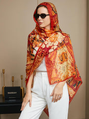 Women's mulberry silk printed rectangle scarf in vibrant orange and red, styled with white pants.