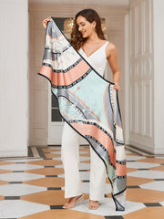 Woman holding a long mulberry silk printed shawl scarf with peach, mint, and grey floral patterns.