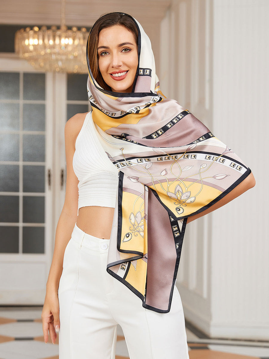 Woman wearing a 100% mulberry silk printed rectangular long shawl scarf with yellow, beige, and brown patterns.