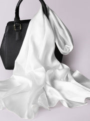 White mulberry silk rectangle long scarf draped over a black handbag.