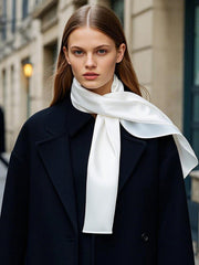 Woman wearing a white mulberry silk rectangle long scarf, tied elegantly over a black coat.