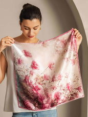 Woman holding a 100% mulberry silk square scarf with a delicate pink rose pattern, 53x53cm.