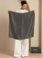 Woman holding a black and white patterned 90x90cm mulberry silk square scarf.