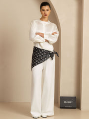 Model wearing a white blouse and wide-leg pants, accented by a black and white patterned mulberry silk square scarf.