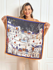 Mulberry silk scarf with a winter village scenery pattern, featuring white snow, colorful houses, and an orange border.