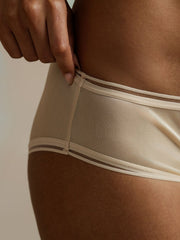 Nude mulberry silk seamless panty with mesh edge detail, shown on a woman's hip.