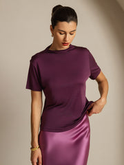 Women's mulberry silk short sleeve mock neck t-shirt in deep purple, paired with a satin skirt.