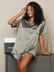 Smiling woman in a loose-fitting olive green 100% mulberry silk short sleeve round neck sleep tee.