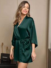 Woman in a dark green 100% mulberry silk short kimono robe with a wrap design and tie waist.