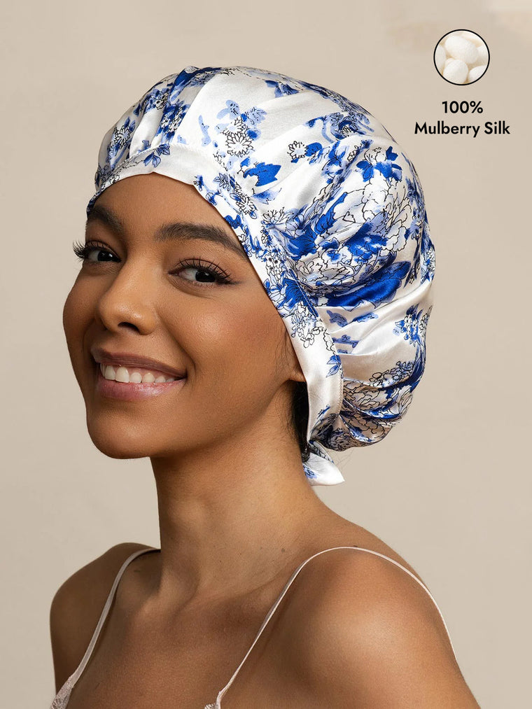 Woman wearing a blue and white porcelain pattern mulberry silk sleep bonnet with ribbons.