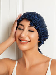 Navy blue mulberry silk sleep cap with ribbon tie on a smiling woman.