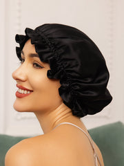 Black mulberry silk sleep cap with ruffled trim, worn by a woman.
