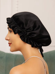 Black mulberry silk sleep cap with ruffled edge and ribbon tie on a woman.