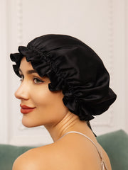 Black double-layer mulberry silk sleep cap with ruffled ribbon detail on a woman.