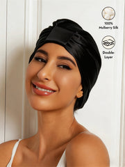 Smiling woman wearing a black, double-layer 100% mulberry silk sleep cap or night turban bonnet.