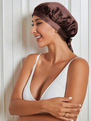 Smiling woman wearing a coffee brown mulberry silk sleep cap with a tie closure, protecting hair.