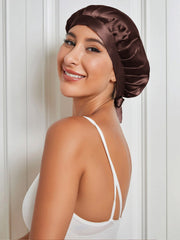 Smiling woman wearing a brown mulberry silk sleep cap with tie closure, protecting hair.
