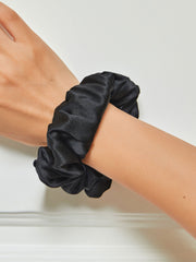 Black mulberry silk scrunchie on a woman's wrist, soft and large hair accessory.