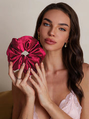 Woman holding a large, soft mulberry silk scrunchie in a rich magenta color.