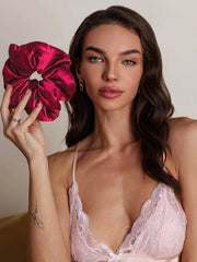 Woman holding a large, shiny mulberry silk scrunchie in a rich magenta color.