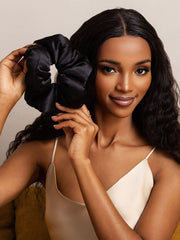 Woman holding a large black 100% mulberry silk scrunchie, soft and oversized.