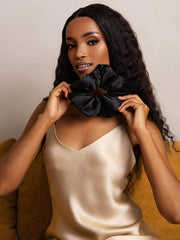 Woman holding a large black mulberry silk scrunchie, showcasing its soft, oversized design.