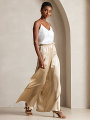 Woman in white mulberry silk camisole and champagne wide-leg silk pants.