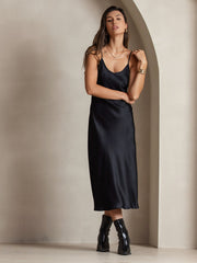 Black mulberry silk spaghetti strap V-neck midi dress on a woman, styled with gold jewelry and boots.