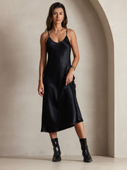 Black 100% Mulberry Silk Spaghetti Strap V Neck Midi Dress on a woman, paired with black boots.
