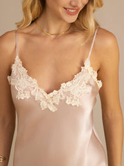 Blonde woman wearing a blush pink mulberry silk spaghetti strap V-neck midi dress with delicate lace trim.