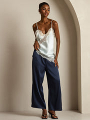 Women's mulberry silk camisole top with lace trim and asymmetrical hem, paired with navy silk pants.