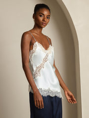 Women's light blue mulberry silk camisole top with white lace trim, spaghetti straps, and asymmetrical hem.