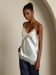 Women's light blue mulberry silk camisole with white lace trim, spaghetti straps, and asymmetrical hem.