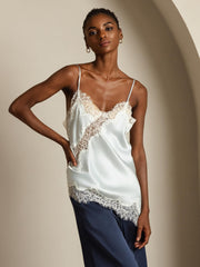 Women's light blue mulberry silk camisole with white lace trim, spaghetti straps, and asymmetrical hem.