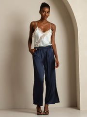 Women's mulberry silk camisole top with lace trim and asymmetrical hem, paired with navy silk pants.