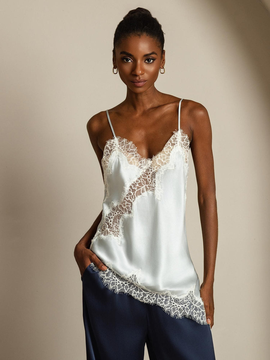 Light blue mulberry silk camisole top with white lace trim and asymmetrical hem, worn by a woman.