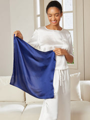 Smiling woman holding a royal blue 100% mulberry silk square scarf, 53x53cm.